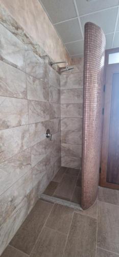 a bathroom with a shower with a stone wall at Nara in Pchelin