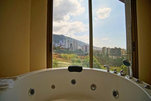a bath tub in a bathroom with a large window at Hotel Xperience in Jounieh