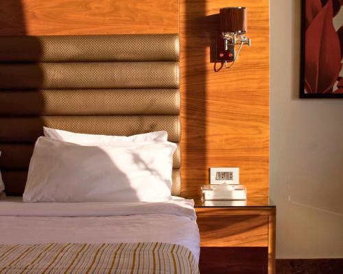 a bed with a wooden headboard and a clock on a table at Hotel Xperience in Jounieh