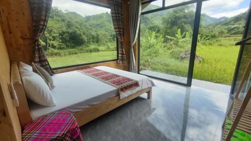 a bedroom with a bed and a large window at Du già Mit's homestay in Yên Minh