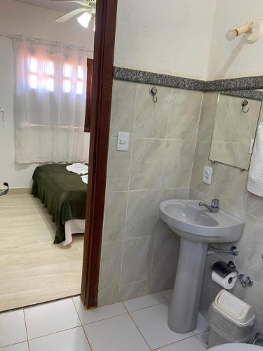 a bathroom with a sink and a shower with a bed at Pousada sollaris in Serra do Cipo
