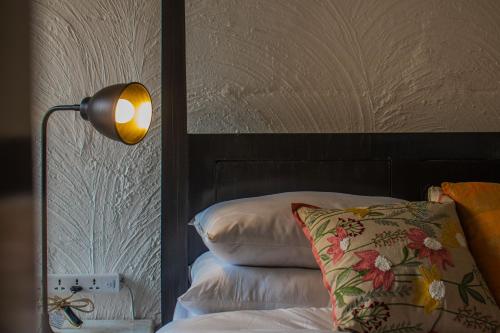 a bedroom with a bed with a lamp and pillows at Baagh-Bohemian 6BHK Farmhouse, Jagatpura, Jaipur in Jaipur
