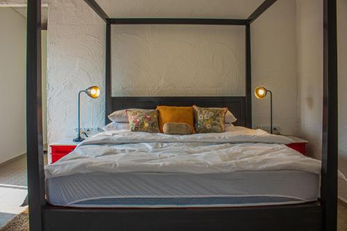 a large bed with a black frame and pillows at Baagh-Bohemian 6BHK Farmhouse, Jagatpura, Jaipur in Jaipur