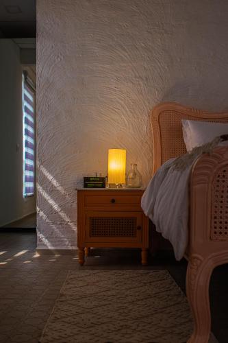 a bedroom with a bed with a lamp on a night stand at Baagh-Bohemian 6BHK Farmhouse, Jagatpura, Jaipur in Jaipur