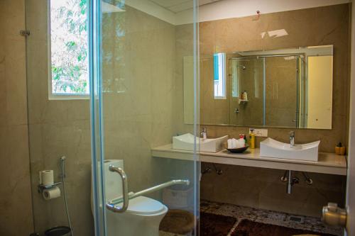 a bathroom with a shower and a toilet and a sink at Baagh-Bohemian 6BHK Farmhouse, Jagatpura, Jaipur in Jaipur