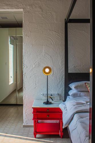 a red table with a lamp on it next to a bed at Baagh-Bohemian 6BHK Farmhouse, Jagatpura, Jaipur in Jaipur