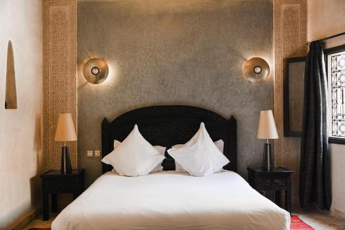 a bedroom with a bed with white sheets and pillows at Les Sources Berbères Riad & Spa in Marrakech