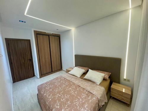 a small bedroom with a bed and a wooden cabinet at Apartment in Mehdia Beach in Kenitra