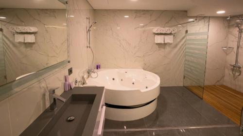 a white bathroom with a tub and a shower at Hotel Xperience in Jounieh