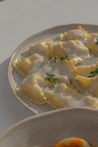 a bowl of dumplings with cheese and greens on it at Olisa Praia Hotel in Maresias