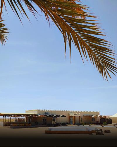 a palm tree with a building in the background at Al Salam Desert Camp Bidiya in Bidiyah