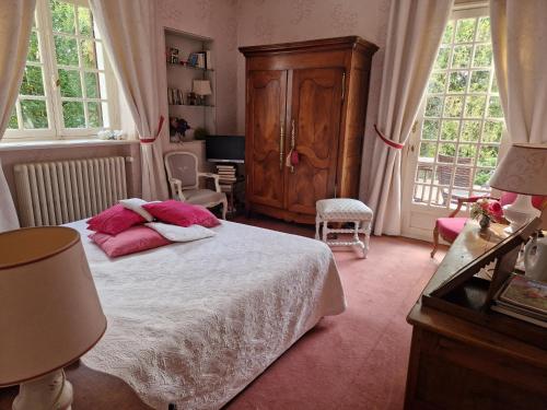 a bedroom with a bed with pink pillows on it at la MAISON de FRAMBOISE in Civray-de-Touraine