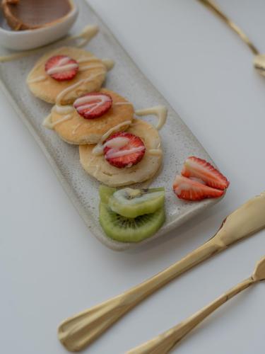 a plate of food with strawberries and kiwis and chopsticks at Olisa Praia Hotel in Maresias