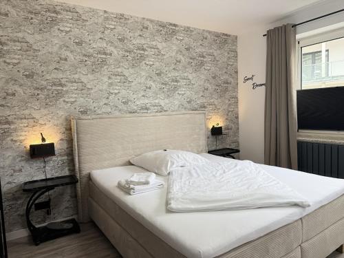 a bed in a bedroom with a brick wall at Oslo: Messe-/Business-/Ferienwohnung in Leichlingen