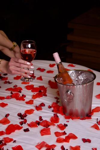 a table with a glass of wine and red rose petals at Hotel Xperience in Jounieh