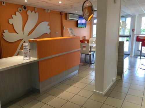 a counter in a restaurant with a flower on the wall at Premiere Classe Toulouse Sud - Portet in Portet-sur-Garonne