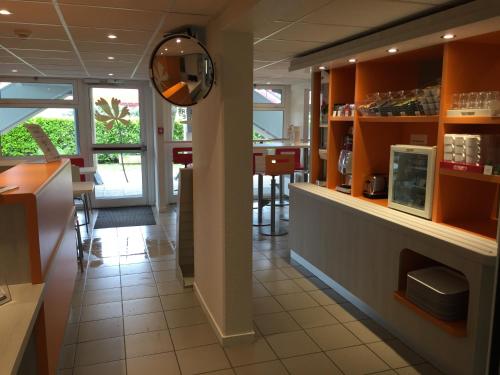 a restaurant with a counter and a kitchen with tables at Premiere Classe Toulouse Sud - Portet in Portet-sur-Garonne