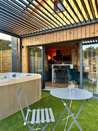 a patio with a table and a tub with chairs at Cosy Lodgy in Eslettes