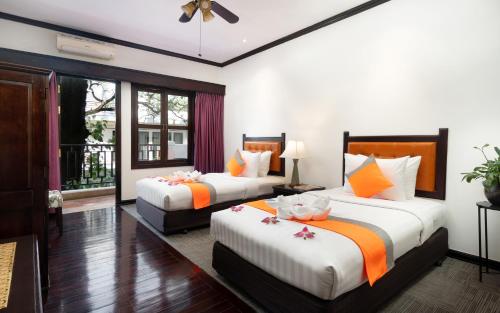 a bedroom with two beds with orange and white sheets at Le Grande Indochine Hotel in Siem Reap