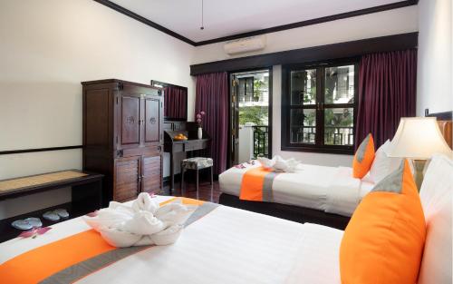 a hotel room with two beds and a desk at Le Grande Indochine Hotel in Siem Reap