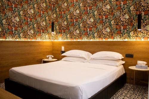 a bedroom with a white bed with a wall at BADIA NUOVA Apart Hotel in Trapani