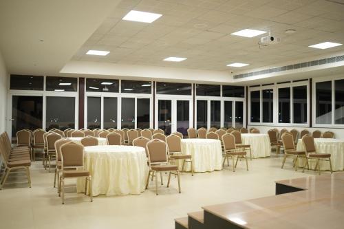 Una sala de conferencias con mesas, sillas y ventanas. en Myspace Hotel JMR, en Chitradurga
