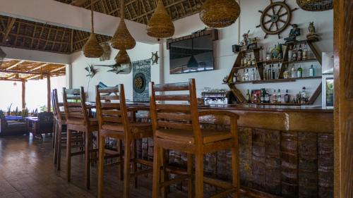 a bar with wooden chairs and a table in a restaurant at Mahi Mahi Beach Hotel in Jambiani