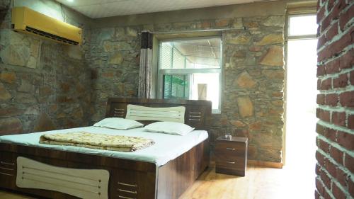 a bedroom with a large bed in a stone wall at Hari Kamal Guest House And Swimming Pool in Dhānd