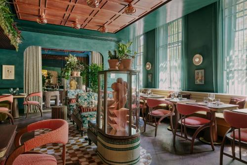 a restaurant with green walls and tables and chairs at Ember Locke Kensington in London