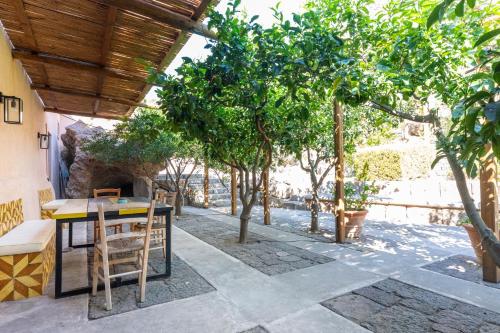 a patio with a table and chairs and trees at Il Frantoio in Panarea
