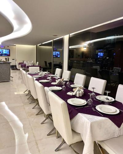 a dining room with a long table and white chairs at Hotel Xperience in Jounieh