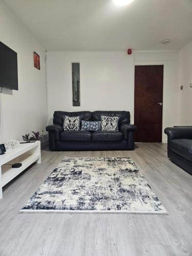 a living room with a black couch and a rug at Cosy 3 Bedroom Bungalow with Private Parking and Rear Garden in Milton Keynes
