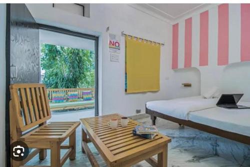 a bedroom with a bed and a table and a chair at Moondance Hostel & Garden Restaurant in Pushkar