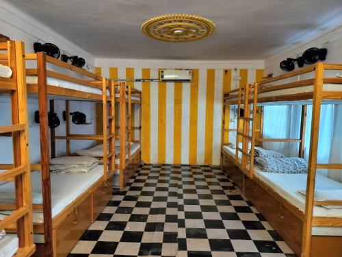 a room with four bunk beds and a checkered floor at Moondance Hostel & Garden Restaurant in Pushkar