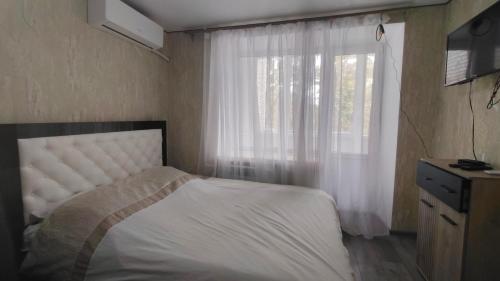 a bedroom with a white bed and a window at Квартира в центре in Mykolaiv