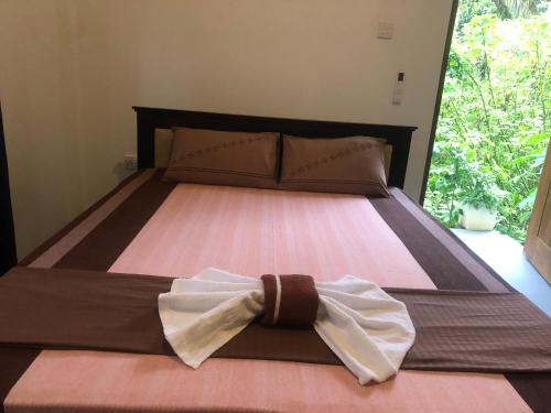 a bed with a bow tie on top of it at Hiri Top Homestay in Dickwella
