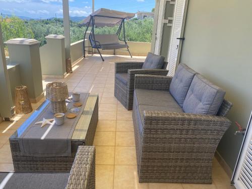 a porch with wicker chairs and a table on a balcony at Elais House Methoni in Methoni