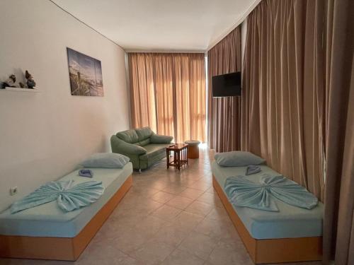 a hotel room with two beds and a chair at Хостел-Lotus in Veliki Preslav