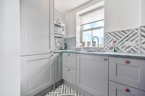 Una cocina blanca con fregadero y ventana. en Perfectly Located, Central Bowness Flat With Free Parking and Lake Views, en Windermere