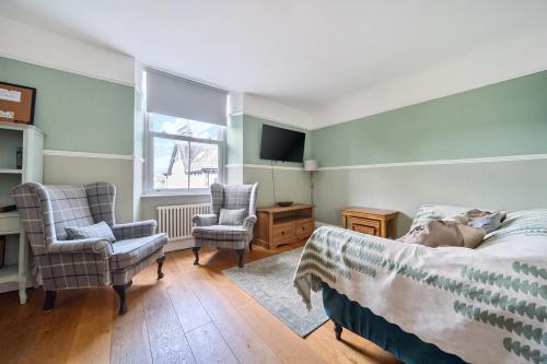 Un dormitorio con una cama y dos sillas y un televisor. en Perfectly Located, Central Bowness Flat With Free Parking and Lake Views, en Windermere