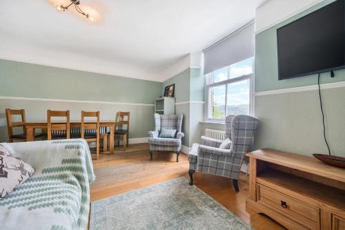 a living room with a flat screen tv and chairs at Perfectly Located, Central Bowness Flat With Free Parking and Lake Views in Windermere