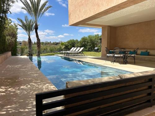 a swimming pool with a table and chairs next to a house at La source d'argan golf villa proche du centre in Marrakech
