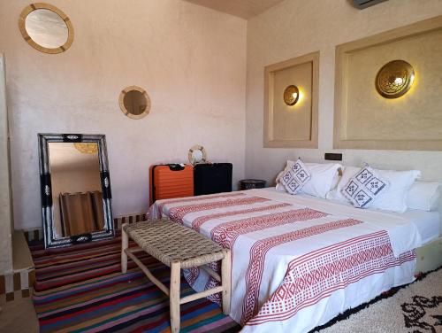 a hotel room with a bed and a mirror at Maison Hassan Merzouga in Merzouga