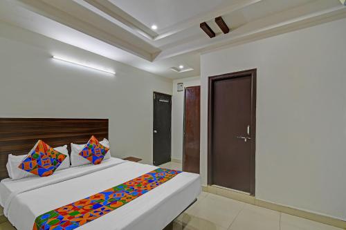 a bedroom with a large white bed with colorful pillows at FabHotel White House Leo in Kondapur
