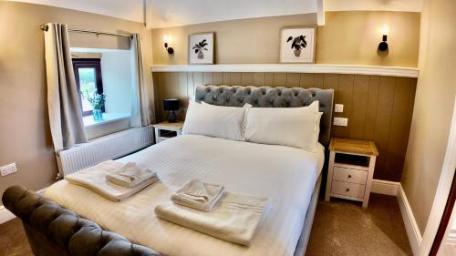 a bedroom with a large bed with towels on it at Bronn Ewhella - Rising Sun Inn in Altarnun