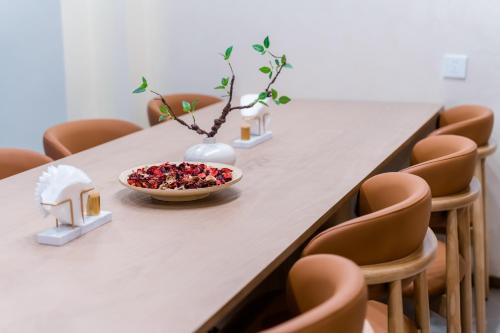 a table with a bowl of fruit on it with chairs at Argyle WAIFIDEN Baolidian Hotel -Free shuttle bus during Canton Fair in Guangzhou