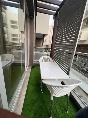 a white bench on a balcony with green grass at Gold Crest Apartments Luxurious in Lahore