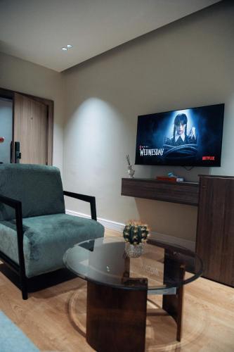 ein Wohnzimmer mit einem grünen Stuhl und einem Flachbild-TV in der Unterkunft Sunny 1-Bedroom with Private Balcony wuse2 in Abuja