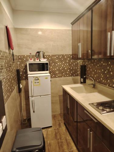 a kitchen with a white refrigerator and a sink at فندق المهاجر للشقق المخدومة بالبوادي in Jeddah