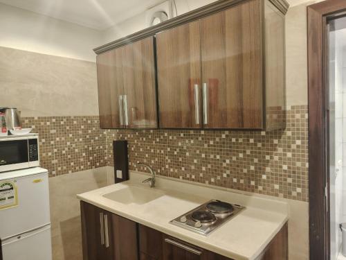 a kitchen with a sink and a microwave at فندق المهاجر للشقق المخدومة بالبوادي in Jeddah